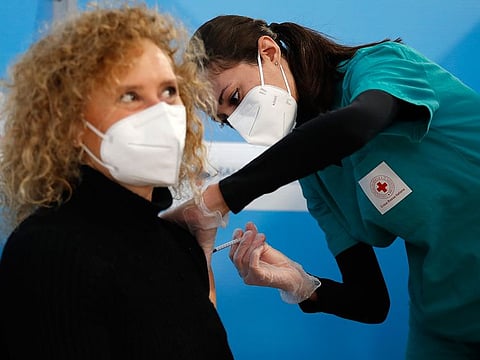 A health worker administers a dose of the AstraZeneca vaccine to a woman at a vaccination center set up in Fiumicino, near Rome's international airport.