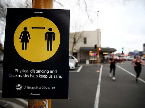 People jog past a social distancing sign on the first day of New Zealand's new coronavirus disease (COVID-19) safety measure that mandates wearing of a mask on public transport, in Auckland, New Zealand, August 31, 2020.