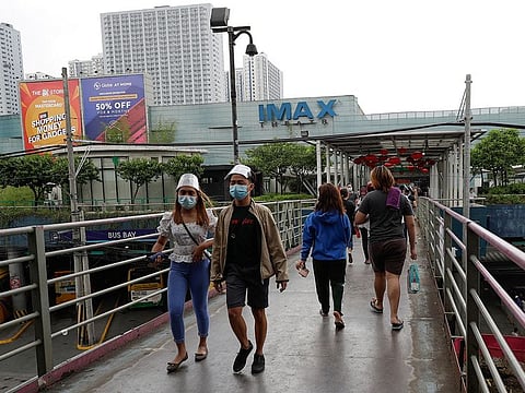 People wearing face mask and shield to prevent the spread of the coronavirus walk outside a mall that houses movie theaters in Quezon City, Philippines.