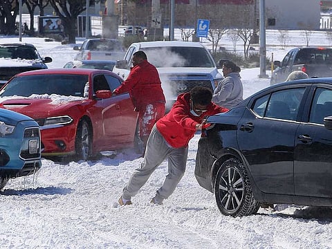 People push a car free after spinning out in the snow in Waco, Texas. A winter storm that brought snow, ice and plunging temperatures across the southern Plains and caused a power emergency in Texas stretched its frigid fingers down to the Gulf Coast.