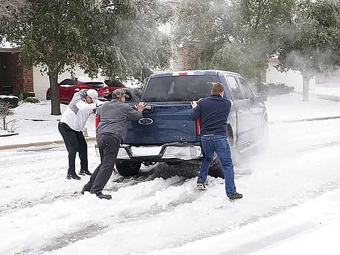 Residents help a pickup driver get out of ice on the road in Round Rock, Texas, on February 17, 2021, after a winter storm.