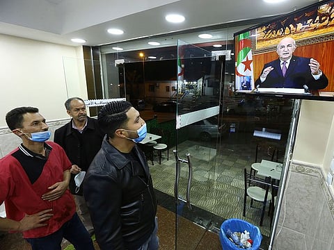 People watch Algerian President Abdelmadjid Tebboune speaking on television, Thursday, Feb.18, 2021 in Algiers.