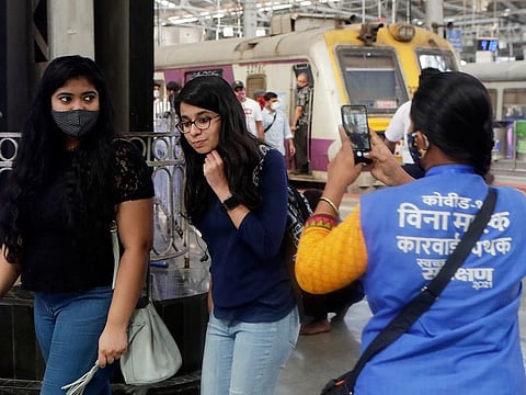 A municipal worker takes visual evidence of a commuter not wearing a face mask in order to give her a penalty at Chhatrapati Shivaji Maharaj Terminus in Mumbai, on February 20, 2021.