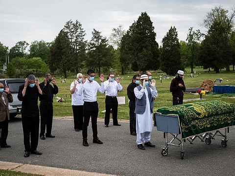 In this file photo taken on May 14, 2020 Imam Said Sherzadi (right) leads close family in prayer near the casket of Ghulam Merzazada, at the National Memorial park cemetery in Fairfax, Virginia on May 14, 2020. The US death toll from COVID-19 is approaching half a million.