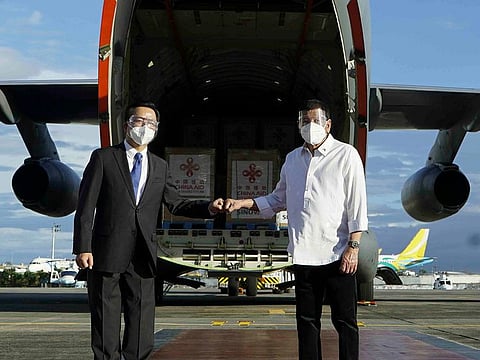 Philippine President Rodrigo Duterte, right, poses with Chinese Ambassador to the Philippines Huang Xilian, second from left, as they stand in front of a military place carrying Sinovac vaccines from China at the Villamor Air Base in Manila, Philippines on Sunday Feb. 28, 2021.