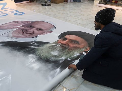 A worker rolls a poster of Pope Francis and Iraq's top Shiite cleric, Ayatollah Ali Al Sistani, ahead of the Pope's planned visit to Iraq, at a shop in Najaf, Iraq, February 28, 2021.