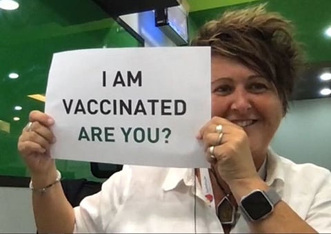 A Global Village staff member holds a placard in solidarity with UAE's vaccination drive against COVID-19.