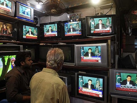 Shopkeepers listen to Pakistan's Prime Minister Imran Khan addressing the nation on television (File)