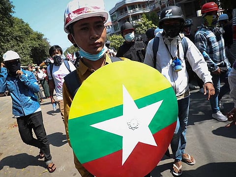 Anti-coup protesters take cover with makeshift shields as armed riot policemen gather in Mandalay, Myanmar, Friday, March 5, 2021.
