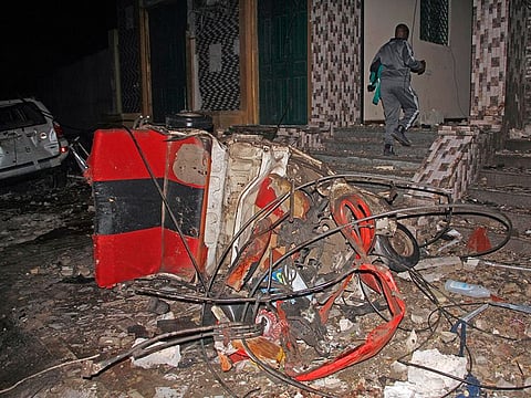A man walks past a destroyed vehicle at the scene of a blast at a popular restaurant in the capital Mogadishu.