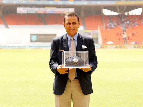 Sunil Gavaskar poses for the photographers with a 'blue baggy' cap, presented to him on the 50th anniversary of his memorable Test debut, by BCCI during Ahmedabad Test on Saturday.