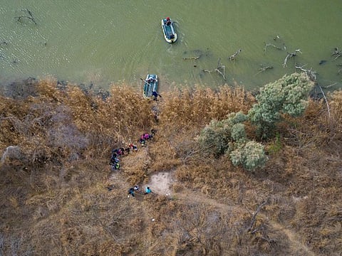 Migrant families and children climb the banks of the Rio Grande River into the United States as smugglers on rafts prepare to return to Mexico in Penitas, Texas, U.S.