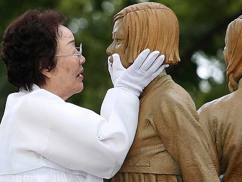 In this Aug. 14, 2019, file photo, Lee Yong-soo, who was forced to serve for the Japanese troops as a sex slave during World War II, touches the face of a statue of a girl symbolising the issue of wartime "comfort women" during its unveiling ceremony in Seoul, South Korea. Harvard University law professor J. Mark Ramseyer alleged in a December 2020 article, scheduled to appear in the March 2021 issue of the International Review of Law and Economics, that the Korean women had actually chosen to work as prostitutes. Lee described Ramseyer's claim as "ludicrous" and demanded an apology.