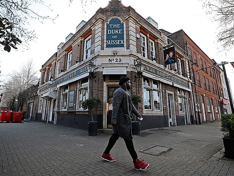 A man walks past the Duke of Sussex restaurant with a sign depicting the image of Britain's Prince Harry and his wife Meghan, near Waterloo station, London, on March 9, 2021.