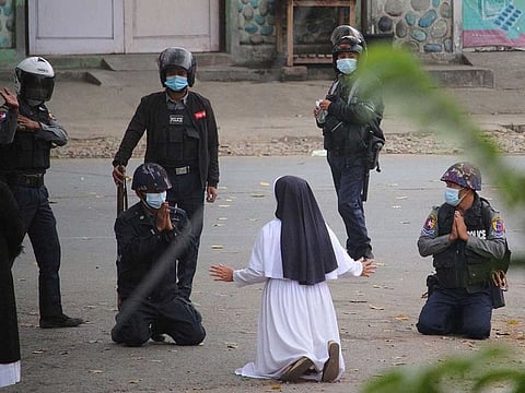 This handout photo taken on March 8, 2021 and released on March 9 by the Myitkyina News Journal shows a nun pleading with police not to harm protesters in Myitkyina in Myanmar's Kachin state, amid a crackdown on demonstrations against the military coup.