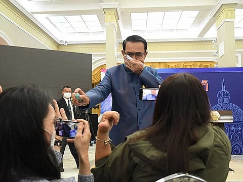 Thailand's Prime Minister Prayuth Chan-ocha sprays alcohol mist on a front row of reporters sitting inside the press conference room at Government house in Bangkok, Thailand, Tuesday, March 9 , 2021. Riled by a final question about a possible Cabinet reshuffle, the prime minister told reporters to mind their own business, then grabbed a container of alcohol mist and doused the front row before sauntering off.