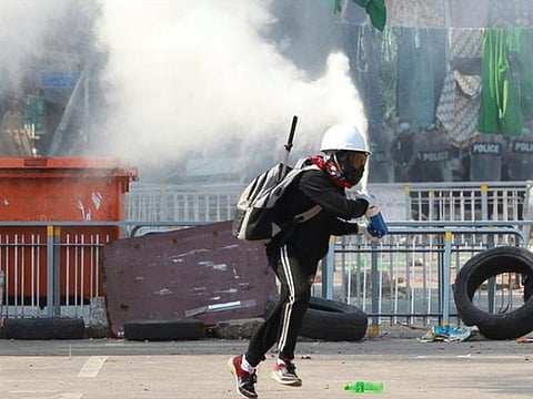 An anti-coup demonstrator sprays a fire extinguisher as he runs away from a barricade during a protests in Yangon, Myanmar.