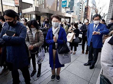 People wearing protective face masks observe a moment of silence outside a Wako Co. department store in the Ginza district of Tokyo, Japan, on Thursday, March 11, 2021.