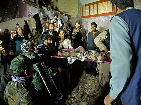 Rescuers carry an injured girl amid the debris of a damaged house after a car bomb blast in Herat.