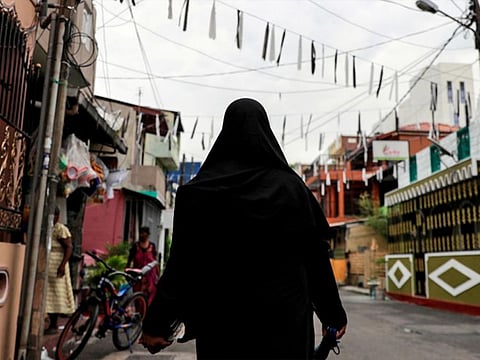 A Muslim woman wearing a burqa walks through a street in Colombo, Sri Lanka.