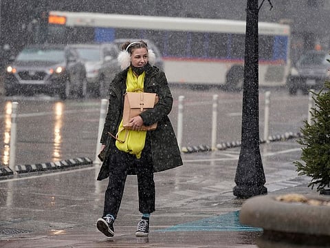 A pedestrian wears ear muffs while walking along 15th Street as a snowstorm sweeps over the intermountain West Saturday, in Denver. Forecasters were predicting up to three feet of snow from the lumbering storm, which started slowly around the noon hour Saturday.