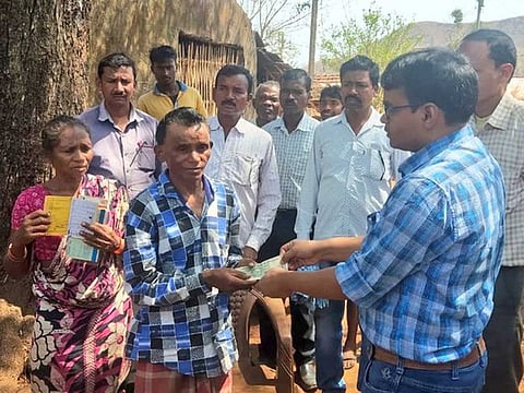 Berjom Bamda Pahadiya, who walked for seven months to reach home, being given cash by an official in Jharkhand.