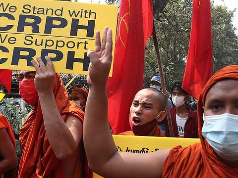 Monks hold placards and gesture with a three-finger symbol of resistance as they protest against the military coup in Mandalay, Myanmar, Friday, March 12, 2021.