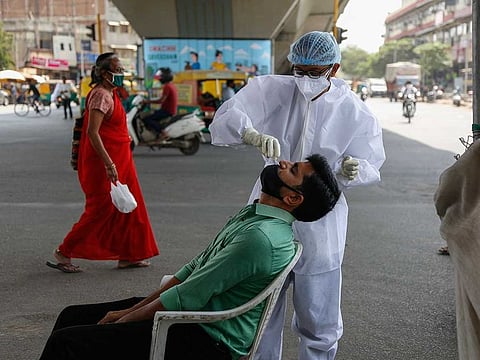A health worker takes a nasal swab sample of a man to test for COVID-19 at a busy street in Ahmedabad, India.