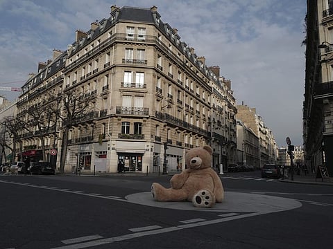 A teddy bear placed on a traffic roundabout by Philippe Labourel, who wants to be named 'Le papa des nounours', 'Teddy Bear father', in Paris, Wednesday, March 3, 2021. Philippe Labourel, a bookshop owner, situated in the Gobelins district of Paris, has been lending out oversized plush creatures since October 2018. Since the pandemic cut short public life in the French capital last year, the bookseller's bears have been spotted sitting at a bus stop and in shops to remind customers of social distancing rules.