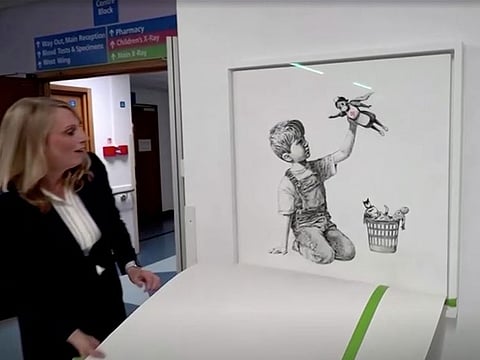 Chief executive of University Hospital Southampton NHS Foundation Trust, Paula Head, unveils Banksy's "Game Changer" artwork, in London, Britain March 16, 2021, in this still image taken from a video