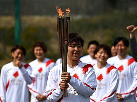 Japanese torchbearer Azusa Iwashimizu, a member of Japan women's national football team, carries the Olympic torch which began it's relay outside J-Village National Training Centre in Naraha, Fukushima Prefecture on Thursday.