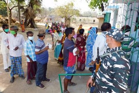 Paramilitary personnel stands guard as voters stand in a queue to cast vote during the first phase of the Assembly elections, in Bankura on Saturday. (ANI Photo)