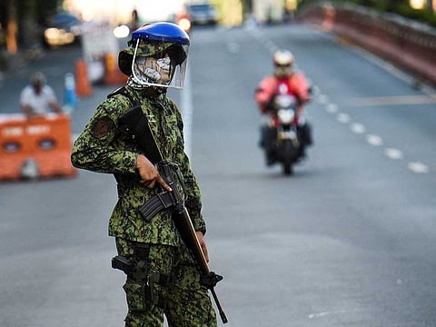 File photo:A policeman wearing a facemask and standing guard at a checkpoint in Manila.