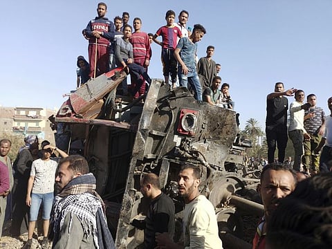 Egyptians gather around mangled train carriages at the scene of a train accident in Sohag, Egypt, Friday, March 26, 2021.