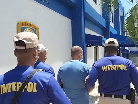 Interpol officers escort Marc Feren Claude Biart, 53, a mafia fugitive who was tracked down thanks to his tattoos visible in cooking videos he posted on YouTube, after arresting him in Boca Chica, Dominican Republic, in this still image taken from video filmed on March 24, 2021.