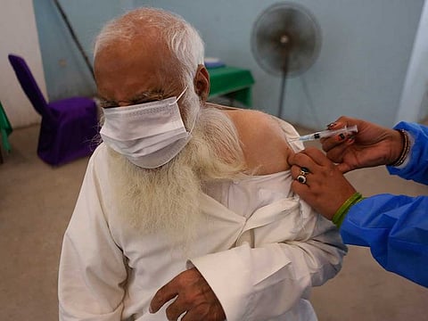 A man reacts while receiving a Sinopharm coronavirus vaccine from a health worker at a vaccination centre in Lahore, Pakistan, Monday, March 29, 2021. AP