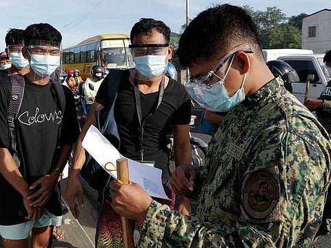 Men show documents at a police checkpoint on the second day of a stricter lockdown to prevent the spread of the coronavirus in the outskirts of Quezon City, Philippines on Tuesday, March 30, 2021.