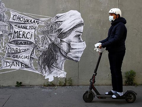 A man rides an electric scooter past a mural by street artist Ardif in Paris, France.