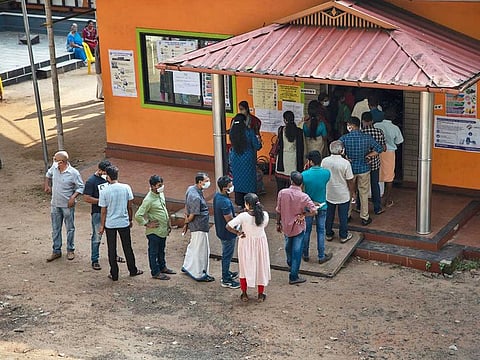 People line up outside a polling booth to cast their votes during the single phase voting for the Kerala state legislature elections in Kochi, India, Tuesday, April 6, 2021.