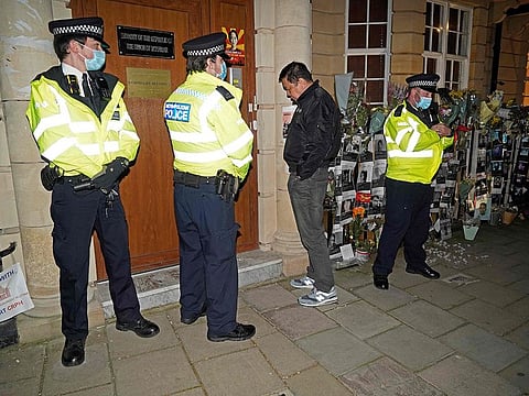 Myanmar's Ambassador to the United Kingdom, Kyaw Zwar Minn, waits unsuccessfully for an answer on the intercom, as police officers stand on duty outside the Myanmar Embassy in London.