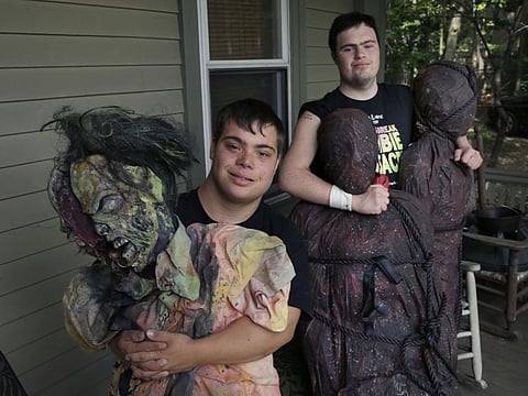 In this July 12, 2016, file photo, Sam Suchmann, right, and Mattie Zufelt pose with ghoulish figures at Sam's home in Providence, R.I. The two young men with Down syndrome who caused a sensation four years ago when they created their own gory zombie movie are back, this time in a documentary championed by a Hollywood luminary that chronicles their tenacious, years-long effort to see their silver screen dream come to fruition.