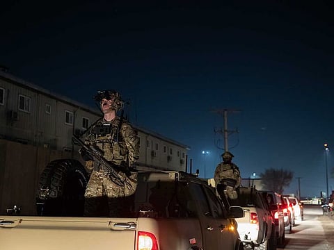 In this Nov. 28, 2019, file photo armed soldiers stand guard in the motorcade as President Donald Trump speaks during a surprise Thanksgiving Day visit to the troops at Bagram Air Field, Afghanistan.