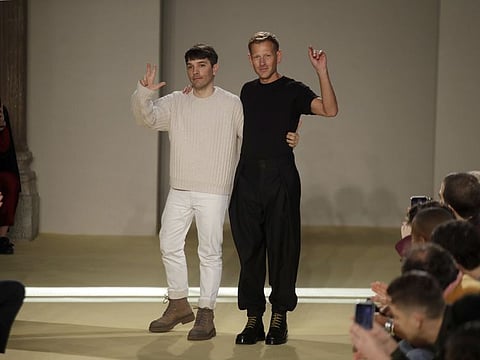 Creative director Paul Andrew, right, accept applause flanked by menswear designer Guillaume Meilland, at the conclusion of the the Salvatore Ferragamo men's Fall-Winter 2020/21 fashion show, that was presented during the fashion week, in Milan, Italy, Sunday, Jan. 12, 2020.