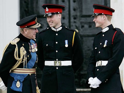 In this April 12, 2006 file photo Britain's Prince Philip, left, talks to his grandsons, Prince William, center, and Prince Harry, right, following The Sovereign's Parade at the Royal Military Academy at Sandhurst, England.