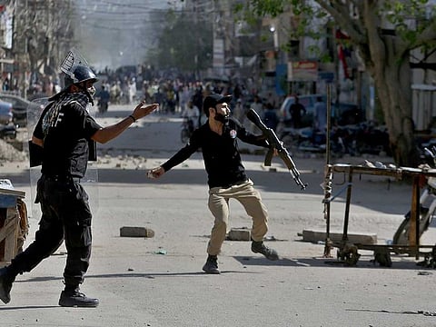 A police officer throws a stone towards angry supporters of Tehreek-e-Labiak Pakistan, a radical Islamist political party, during a clash following the arrest of their party leader Saad Rizvi, in Karachi, Pakistan, Tuesday, April 13, 2021. Two demonstrators and a policeman were killed Tuesday in violent clashes between Islamists and police in Pakistan, hours after authorities arrested Rizvi in the eastern city of Lahore, a senior official and local media reported.