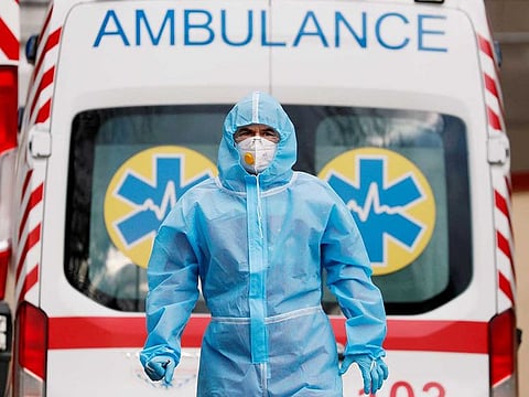 A medical worker wearing protective gear stands next to an ambulance outside a hospital for patients infected with COVID-19.