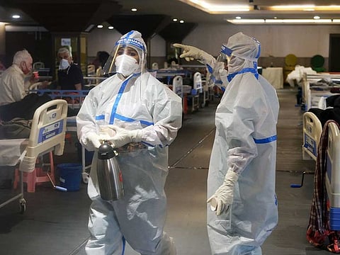 Health workers in personal protective equipment (PPE) care for patients at a makeshift COVID-19 quarantine facility set up in a banquet hall in New Delhi, India, on Tuesday, April 13, 2021.