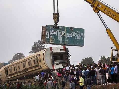 A crane lifts an overturned passenger carriage after a railway accident in the city of Toukh in Egypt's central Nile Delta province of Qalyubiya on April 18, 2021.