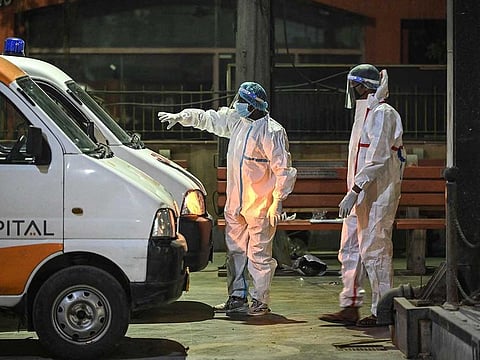 Crematorium staff members stand near ambulances carrying the bodies of COVID-19 victims for a cremation at Nigambodh Ghat Crematorium, on the banks of the Yamuna river in New Delhi in the early hours of April 22, 2021.