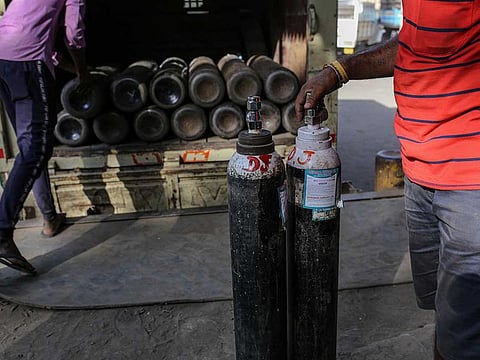 Workers load refilled oxygen tanks into a vehicle at a refill station in Mumbai on April 22, 2021. India has faced a severe shortage in oxygen supply to treat COVID-19 patients.